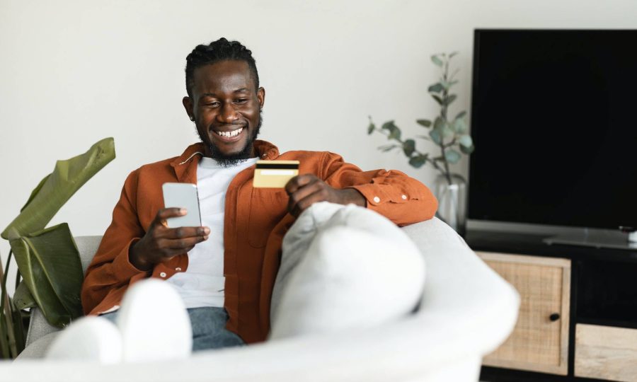 Fast online shopping concept. Positive african american man making financial transaction with credit